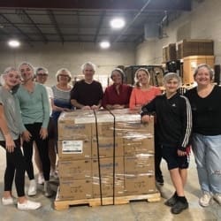 People standing around a pallet of boxes